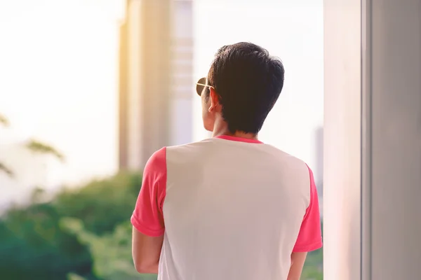 Hombre en camiseta rosa y blanca mirando hacia el exterior al atardecer . — Foto de Stock