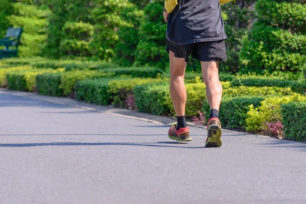 Closeup of runner is jogging in urban garden. — Stock Photo, Image