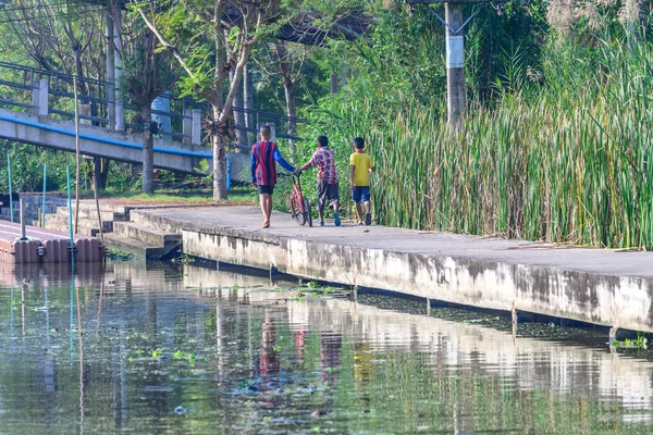 Boys walking along the canal with bicycle. — Stock Photo, Image