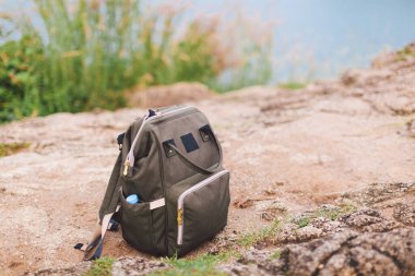 Hipster haki rengi sırt çantası yakın plan ön manzara turist çantası arka planda. Yürüyüşten sonra sırt çantası yerde dinleniyor. Yürüyüş yapmak ve sırt çantası konseptiyle seyahat etmek. Boşluğu kopyala