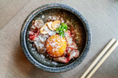 Omakase yemeği: Orta pişmiş A5 Hakoshima Wagyu bifteği ızgara edilmiş suşi pilavı, üzerinde yumurta sarısı, kıymalı soğan ve Himalaya tuzu. Japon geleneksel ve lüks yemeği.