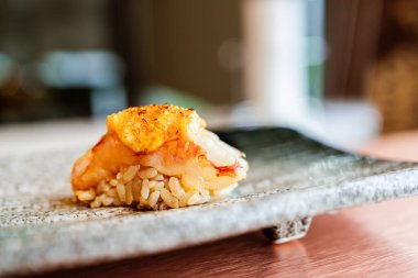 Japon Omakase yemeği: Meşale Mentaiko soslu ızgara karides suşisi taştan bir tabakta elle servis edilir. Japon geleneksel ve lüks yemeği.