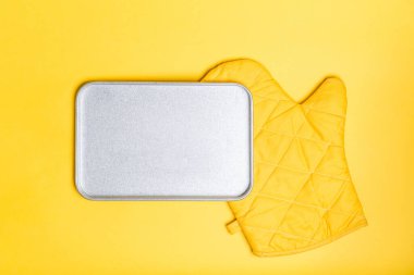 Empty bake plate place over yellow oven gloves on yellow color background. Mockup for food banner. clipart