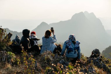 Chiang Mai, Tayland. 18 Şubat 2019: Yalıtılmış ceket, ceket ve eşarp giyen maceraperest ve turistler, Doi Luang, Chiang Dao 'nun arka planında gün batımının ve dağların fotoğraflarını çekiyorlar..