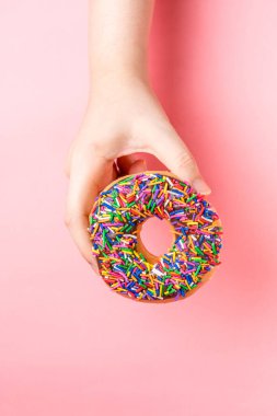 Pembe arka planda çikolata soslu donutla el ele tutuşmanın en iyi görüntüsü. Fotokopi alanı olan müşteriler için eğlenceli ve keyifli, tatlı, rahatlatıcı yemekler..