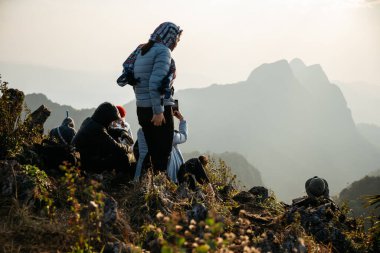 Chiang Mai, Tayland. 18 Şubat 2019: Yalıtılmış ceket, ceket ve eşarp giyen maceraperest ve turistler, Doi Luang, Chiang Dao 'nun arka planında gün batımına yakın dağ ve alacakaranlıkla ayakta duruyorlar..
