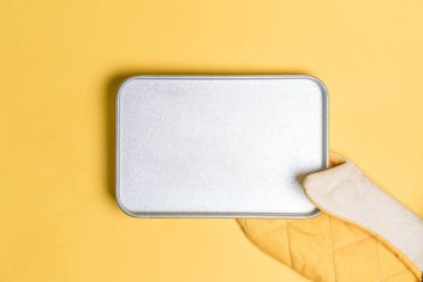 Empty bake plate place inside yellow oven gloves on yellow color background. Mockup for food banner. clipart