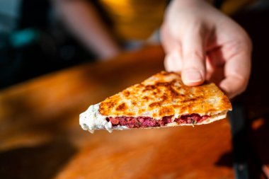 El ele tutuşan Vegan Quesadilla: Tzaziki soslu vegan peynirli tatlı patates ve kırmızı fasulyeyle dolu ızgara tam buğday tortilla. Yaratıcı Meksika vejetaryen yemekleri.