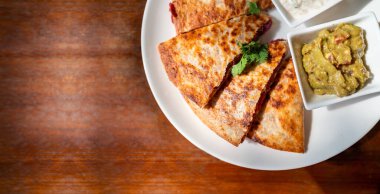 Vegan Quesadilla 'nın ekin görüntüsü: tatlı patates ve fasulye dolu ızgara tam buğday tortilla, guacamole salsa ve Tzaziki soslu vejetaryen peyniri..