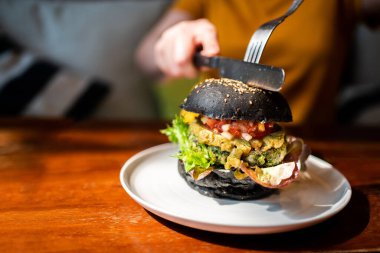 El kesimi Brokoli kinoa kömür burgeri üzerine guacamole sosu, mango sosu ve çatal ve bıçakla taze salata, beyaz bir tabakta servis edilir. Vejetaryenler için yaratıcı vejetaryen yemeği.