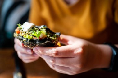 Elleri ısırılmış Brokoli kinoa kömür burgeri üzerine guacamole sosu, mango sosu ve yarısı kesilmiş taze salata. Vejetaryenler için yaratıcı vejetaryen yemeği.