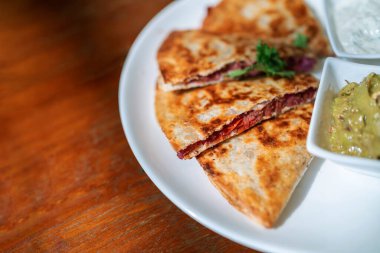 Vegan Quesadilla 'nın yakın çekimi: patatesle dolu ızgara tam buğday tortilla, guacamole soslu vegan quesso peyniri ve Tzaziki sosu..