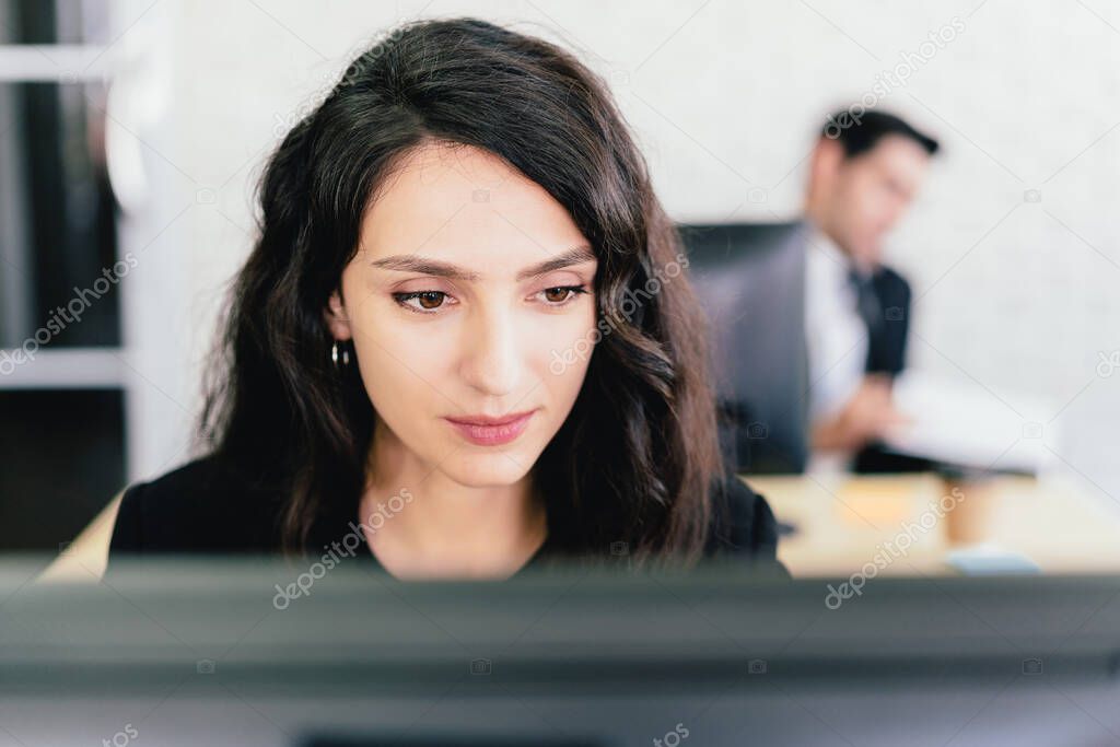 Close-up portrait of a Caucasian businesswoman typing and looking on a computer screen with intention at her desk. Concern and fix problems in a corporate office.