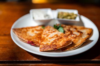 Vegan Quesadilla 'nın yakın çekimi: patatesle dolu ızgara tam buğday tortilla, guacamole soslu vegan quesso peyniri ve Tzaziki sosu..
