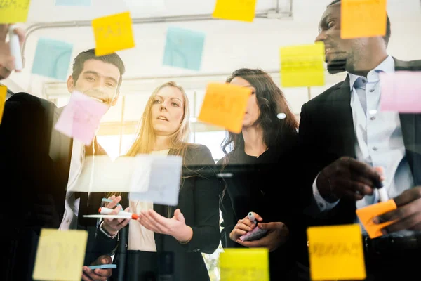 Başarılı bir takım çalışması grubu. Yeni fikirler için cam duvara renkli yapışkan kağıt notlarla beyin fırtınası toplantısı. Çevik metodolojiyi kullanarak ve iş yaparak. Bir teknoloji şirketinde beyin fırtınası..
