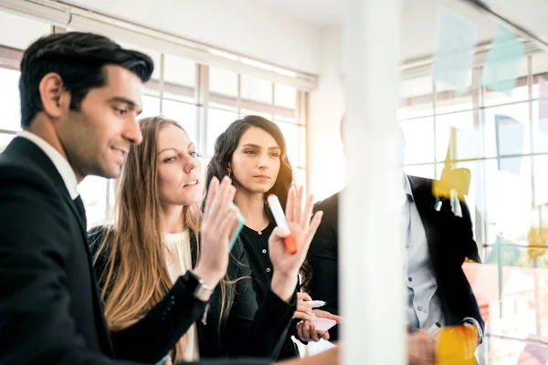 Başarılı bir takım çalışması grubu. Yeni fikirler için cam duvara renkli yapışkan kağıt notlarla beyin fırtınası toplantısı. Çevik metodolojiyi kullanarak ve iş yaparak. Bir teknoloji şirketinde beyin fırtınası..