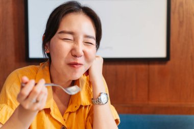 Asyalı bir kadın modern bir kafede donut yemekten mutlu. Kadın yaşam tarzının keyfi.