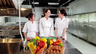 Profesyonel bir aşçılık kursunda taze sebzelerle iki genç aşçılık öğrencisine yemek öğretiyor. Aşçılık eğitimi, gastronomi ve gıda eğitimi konuları için ideal..