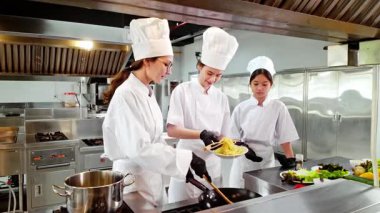 Aşçılık eğitimi sırasında aşçı eğitmeni ve iki öğrenci ticari bir mutfakta yeni pişmiş makarna tadıyorlar. Şef okulunu, aşçılık eğitimini ve yemek becerilerini desteklemek için mükemmel..
