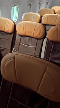 Deri koltukları ve çevre aydınlatması olan boş bir modern uçak kabininin geniş açılı görüntüsü, ticari havayolu oturma düzenini, iç tasarımı, rahatlığı ve seyahat hazırlığını gösteriyor.