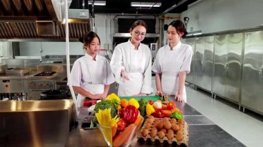 Profesyonel bir aşçılık kursunda taze sebzelerle iki genç aşçılık öğrencisine yemek öğretiyor. Aşçılık eğitimi, gastronomi ve gıda eğitimi konuları için ideal..