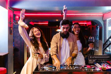 Çeşitli bir grup genç arkadaş, neşeli bir gece kulübü partisinde neşeli bir ışık ve enerjik bir atmosferle gülüp eğleniyorlar. Gece hayatı, kutlama, neşe ve gençlik kültürünü yakalıyorlar..