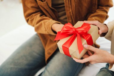 Bir insan, bir diğerine kırmızı kurdeleli güzel bir hediye verir. Kutlama, nezaket ve bağlantıyı sembolize eder. Sevgililer Günü, doğum günleri ya da yıl boyu anlamlı anlar için idealdir..