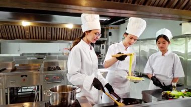 Aşçılık eğitimi sırasında aşçı eğitmeni ve iki öğrenci ticari bir mutfakta yeni pişmiş makarna tadıyorlar. Şef okulunu, aşçılık eğitimini ve yemek becerilerini desteklemek için mükemmel..