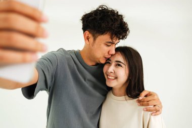 Mutlu bir çift, kapalı bir ortamda selfie çekerken kucaklaşır ve gülümser. Teknoloji, yaşam tarzı ve Sevgililer Günü konsepti