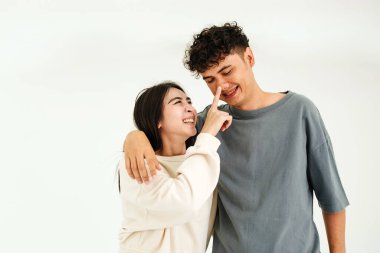 Sevgi ve bağları paylaşan neşeli bir çift, sevgililer günü promosyonları ve yaşam tarzı görselleri için minimalist, iyi ışıklandırılmış bir mekanda eğlenceli bir şekilde etkileşim içindedir.