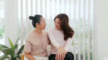 İki kadın. Anne ve kızı evlerinde dikey jaluzilerde oturup gülüyor ve sohbet ediyorlar yeşil ev bitkileriyle dolu sıcak, samimi bir aile anını yakalıyorlar..