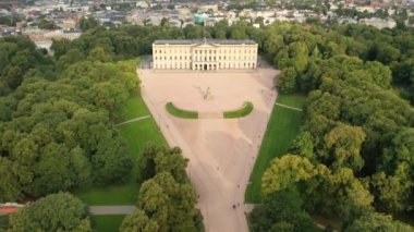 Oslo, Norveç. Kral Karl Johan Oslo 'nun Kraliyet Sarayı ve Heykeli' ne uçan insansız hava aracından güzel 4K panoramik video. Arka planda kale parkı, şehir ve dağlar (Seriler))