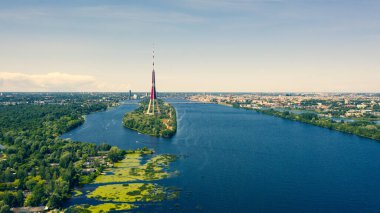 Riga, Latvija. Uçan İHA 'dan Riga Radyo ve Televizyon Kulesi Riga' ya güzel bir panoramik hava görüntüsü. Arka planda Zakusala, Daugava nehri ve Riga şehri güneşli bir yaz gününde. (Seriler)