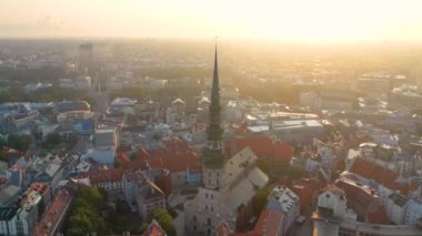 Riga, Letonya, Baltık. St. Peter Kilisesi 'ndeki ve Daugava Nehri' nin arka planındaki Eski Riga Kasabası 'ndaki insansız hava aracının güzel panoramik 4K videosu.