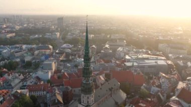 Riga, Letonya, Baltık. St. Peter Kilisesi 'ndeki ve Daugava Nehri' nin arka planındaki Eski Riga Kasabası 'ndaki insansız hava aracının güzel panoramik 4K videosu.