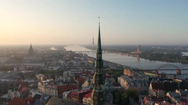 Riga, Letonya, Baltık. St. Peter Kilisesi 'ndeki ve Daugava Nehri' nin arka planındaki Eski Riga Kasabası 'ndaki insansız hava aracının güzel panoramik 4K videosu.