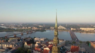 Riga, Letonya, Baltık. St. Peter Kilisesi 'ndeki ve Daugava Nehri' nin arka planındaki Eski Riga Kasabası 'ndaki insansız hava aracının güzel panoramik 4K videosu.