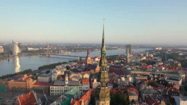 Riga, Letonya, Baltık. St. Peter Kilisesi 'ndeki ve Daugava Nehri' nin arka planındaki Eski Riga Kasabası 'ndaki insansız hava aracının güzel panoramik 4K videosu.