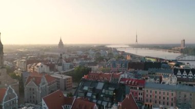 Riga, Letonya, Baltık. St. Peter Kilisesi 'ndeki ve Daugava Nehri' nin arka planındaki Eski Riga Kasabası 'ndaki insansız hava aracının güzel panoramik 4K videosu.
