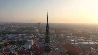 Riga, Letonya, Baltık. St. Peter Kilisesi 'ndeki ve Daugava Nehri' nin arka planındaki Eski Riga Kasabası 'ndaki insansız hava aracının güzel panoramik 4K videosu.