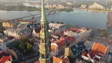 Riga, Letonya, Baltık. St. Peter Kilisesi 'ndeki ve Daugava Nehri' nin arka planındaki Eski Riga Kasabası 'ndaki insansız hava aracının güzel panoramik 4K videosu.