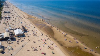 Dzintari, Jurmala, Letonya, Baltık. Sıcak ve güneşli bir yaz gününde Baltık Denizi 'nde güneşlenen ve yüzen insanlarla dolu Dzintari kumlu plajına uçan dron panoramiklerinden havadan çekilmiş bir fotoğraf. (Seriler)