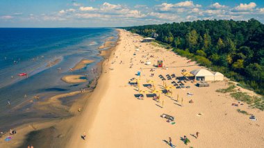 Dzintari, Jurmala, Letonya, Baltık. Sıcak ve güneşli bir yaz gününde Baltık Denizi 'nde güneşlenen ve yüzen insanlarla dolu Dzintari kumlu plajına uçan dron panoramiklerinden havadan çekilmiş bir fotoğraf. (Seriler)