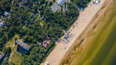 Dzintari, Jurmala, Letonya, Baltık. Sıcak ve güneşli bir yaz gününde Baltık Denizi 'nde güneşlenen ve yüzen insanlarla dolu Dzintari kumlu plajına uçan dron panoramiklerinden havadan çekilmiş bir fotoğraf. (Seriler)
