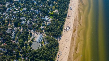Dzintari, Jurmala, Letonya, Baltık. Sıcak ve güneşli bir yaz gününde Baltık Denizi 'nde güneşlenen ve yüzen insanlarla dolu Dzintari kumlu plajına uçan dron panoramiklerinden havadan çekilmiş bir fotoğraf. (Seriler)