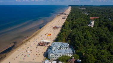 Majori, Jurmala, Letonya, Baltık. Sıcak ve güneşli bir yaz gününde, Baltık Denizi 'nde güneşlenen ve yüzen insanlarla dolu Majori kumsalına insansız hava aracı panoramik uçuşundan havadan çekilmiş bir fotoğraf. (Seriler)