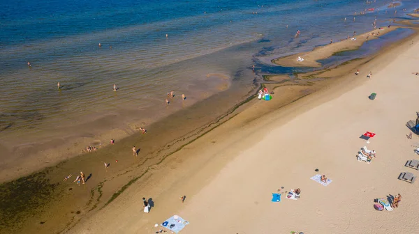 Dzintari, Jurmala ,Latvia, Baltics. Aerial view photo from flying drone panoramic to Dzintari sandy beach full of people sunbathing and swimming in the Baltic Sea on a hot and sunny summer day. (Series)