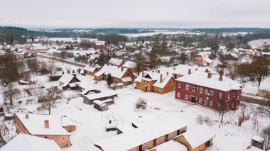 Akniste, Jekabpils, Letonya, Baltık. Kışın insansız hava aracından Akniste şehrine kadar uzanan güzel panoramik hava manzaralı fotoğraf. Küçük kasaba ve ormanlarda kar yağışlı bir kış manzarası. (seri)