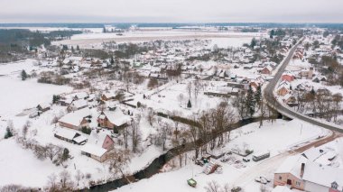 Akniste, Jekabpils, Letonya, Baltık. Kışın insansız hava aracından Akniste şehrine kadar uzanan güzel panoramik hava manzaralı fotoğraf. Küçük kasaba ve ormanlarda kar yağışlı bir kış manzarası. (seri)