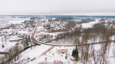 Akniste, Jekabpils, Letonya, Baltık. Kışın insansız hava aracından Akniste şehrine kadar uzanan güzel panoramik hava manzaralı fotoğraf. Küçük kasaba ve ormanlarda kar yağışlı bir kış manzarası. (seri)